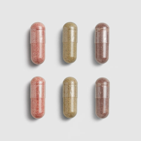Six Juice Plus+ capsules, three pink and three beige, arranged in two rows on a light gray background.