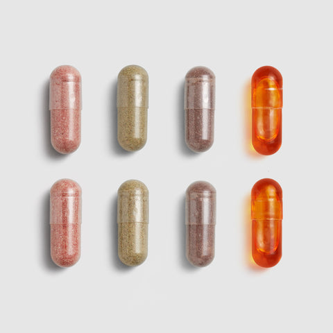 Nine Juice Plus+ capsules in different colors arranged on a light gray background