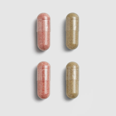 Two pink and two beige Juice Plus+ capsules on a light gray background