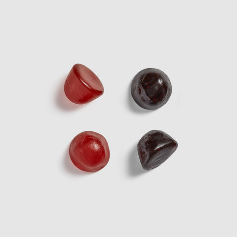 Four red and black Juice Plus+ chewables on a light gray background