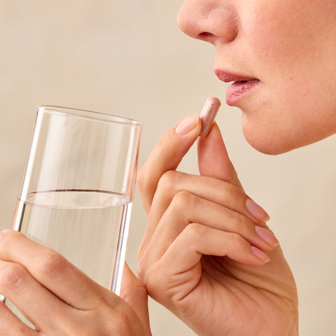 Person holding a Juice Plus+ capsule near a glass of water