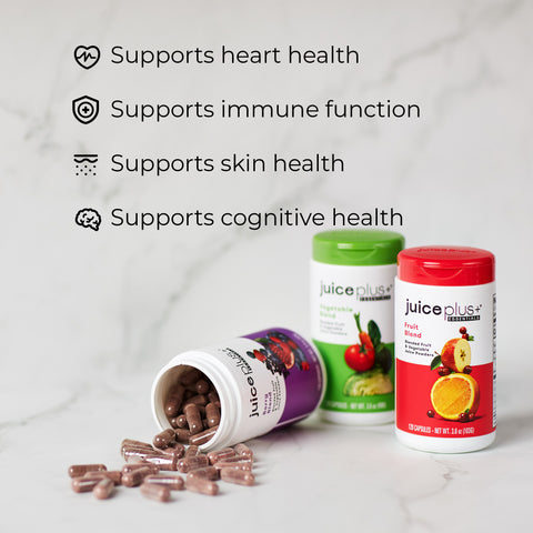 Juice Plus+ supplement bottles with capsules on a marble surface, featuring text about health benefits.