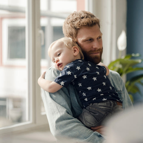 Man holding a child in a home setting with natural light
