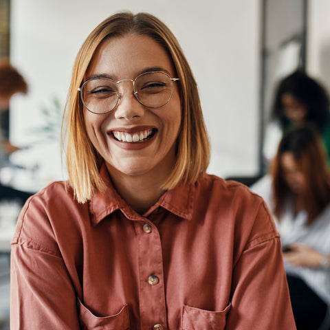 Woman wearing glasses and a red shirt smiling in an office setting
