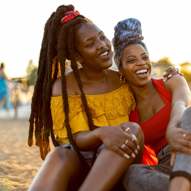 Two women sitting together outdoors, smiling and enjoying each other's company.