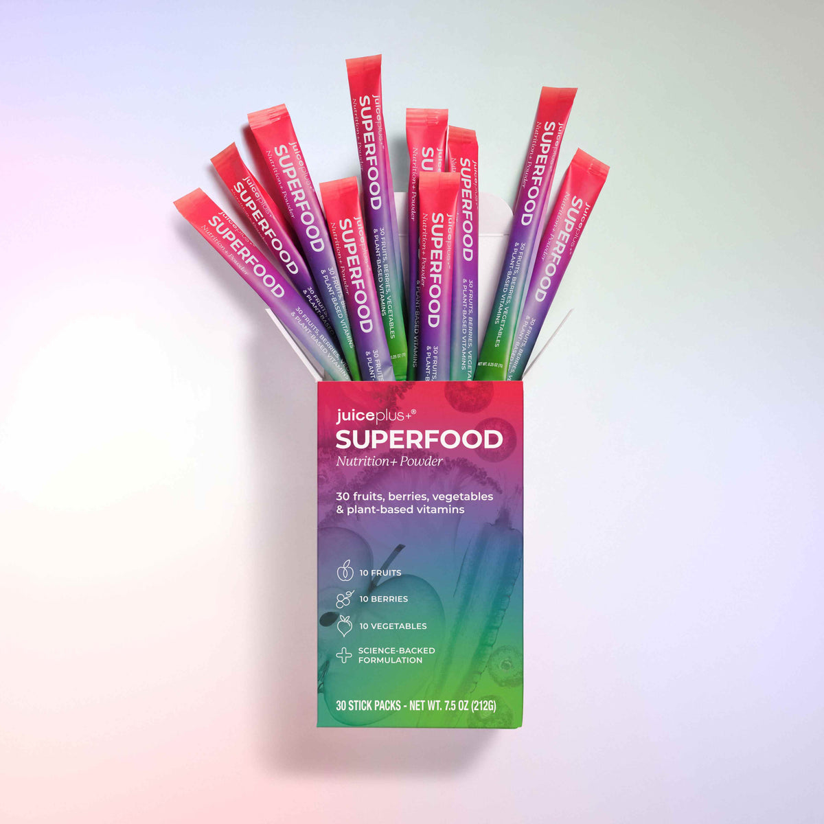 A box of Nature's One Superfood Nutrition+ Powder with multiple colorful stick packs fanned out above it on a soft pastel gradient background.