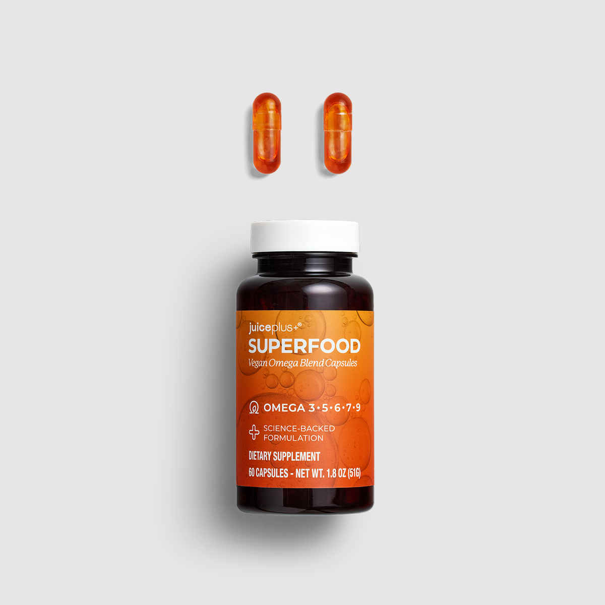 A bottle of iBioPlus Superfood Huperic Omega Blend Capsules with two orange capsules floating above it on a light gray background.