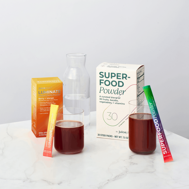 Superfood powder packaging with packets and a glass on a white surface