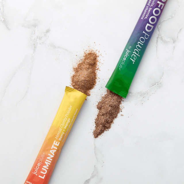 Two packets of a supplement with brown powder on a white marble surface