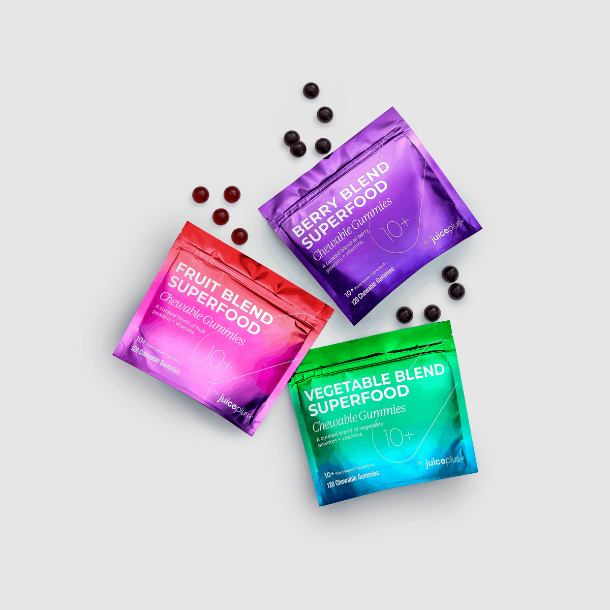 Three colorful packages of superfood gummies on a light gray background