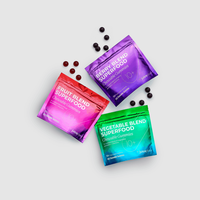 Three colorful packages of superfood gummies on a light gray background