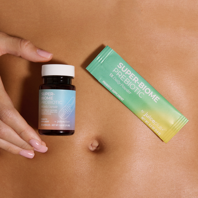 Juice Plus+ Super-Biome bottle and packaging on a person's stomach